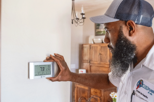 Wisler AC technician adjusting thermostat after air conditioning installation.